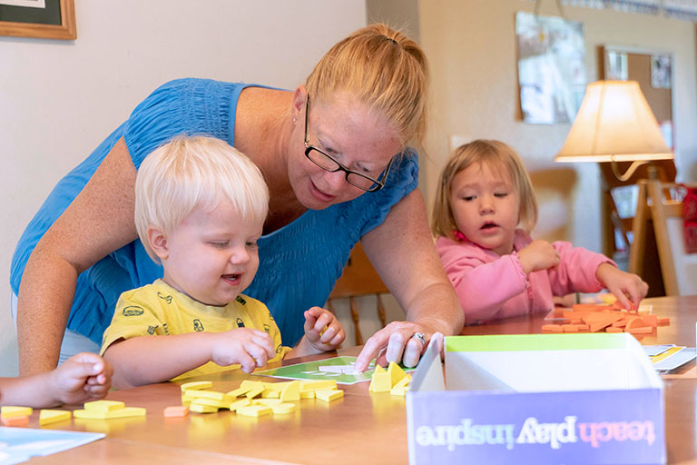 Woman working with toddler on learning game